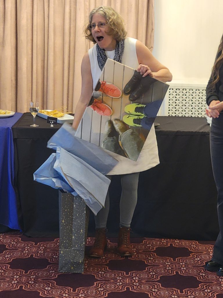 Co-Director Emeritus Batya Friedman opens her gift of a print of the directors' meeting.