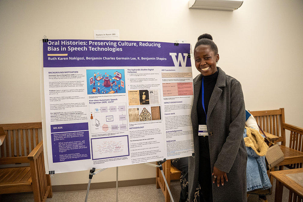 Ruth Nakigozi stands next to a posterboard highlighting her research project on oral histories